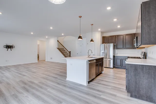 a large kitchen with stainless steel appliances kitchen island a large counter top and a wooden floors
