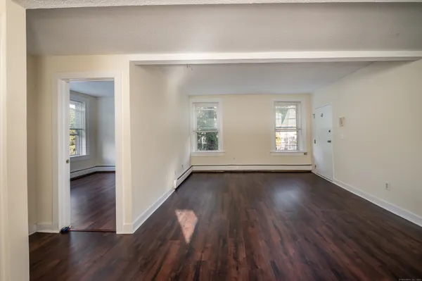 a view of an empty room with wooden floor and a window