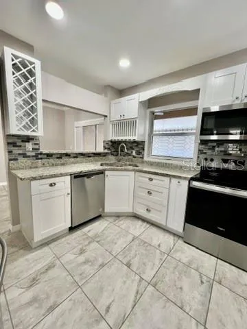 a kitchen with stainless steel appliances granite countertop a stove a sink and a refrigerator