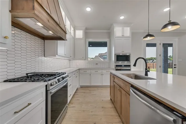a kitchen with white cabinets a sink and appliances