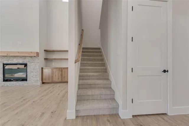 a view of an empty room with wooden floor and a fireplace