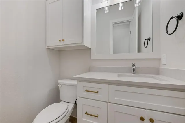 a bathroom with a granite countertop toilet sink and mirror
