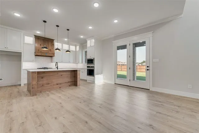 a view of kitchen with stainless steel appliances granite countertop a stove top oven a sink dishwasher and a refrigerator with wooden floor