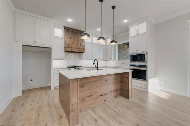 a large kitchen with cabinets wooden floor and a sink