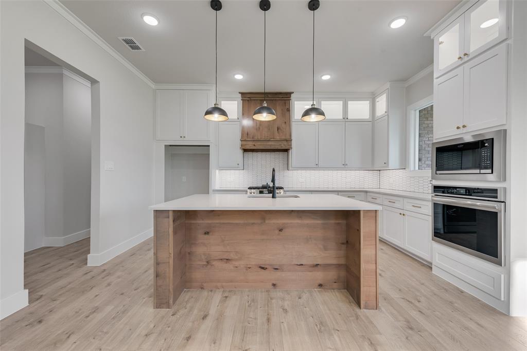 1342 Benjamin Trail Van Alstyne, TX 75495 - Photo 8 of 39 a view of a kitchen with a sink and dishwasher a fireplace with wooden floor