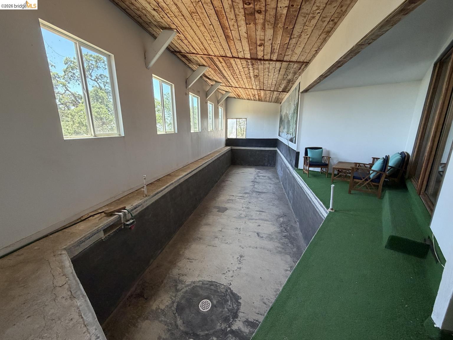 18195 Wards Ferry Road Sonora, CA 95370 - Photo 63 of 67 Indoor pool structure with exposed wood ceiling beams, multiple windows, and a green turf poolside area