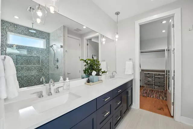 a spacious bathroom with a double vanity sink a large mirror and shower