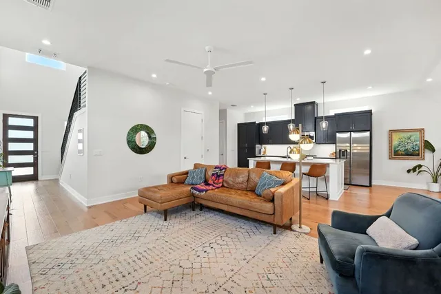 a living room with furniture kitchen view and a wooden floor