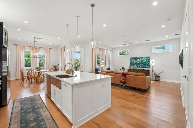 a large kitchen with stainless steel appliances a stove a sink dishwasher and a dining table with the living room view