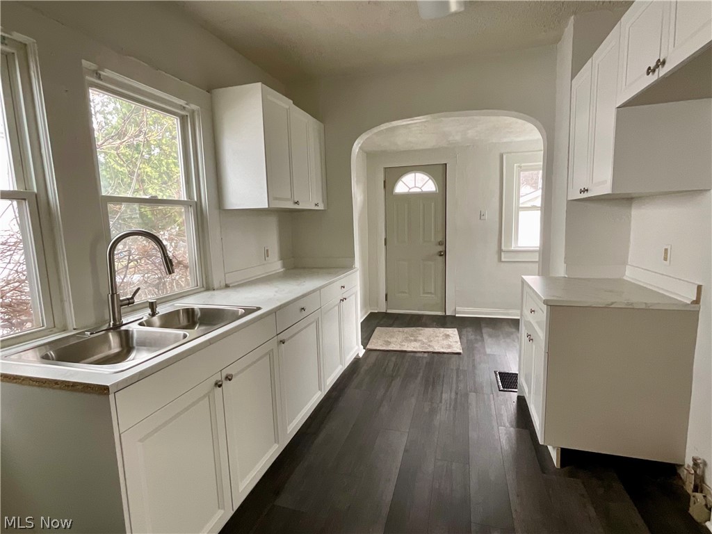 425 Spaulding Street Akron, OH 44310 - Photo 5 of 17 Kitchen featuring white cabinets, light countertops, dark wood-style floors, and arched walkways