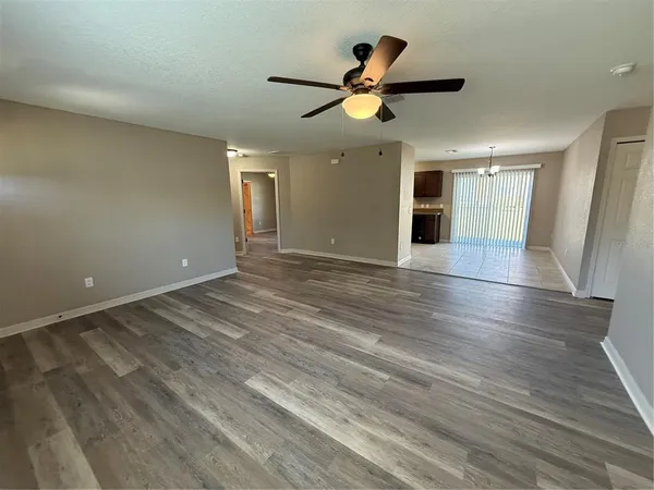 an empty room with wooden floor ceiling fan and windows