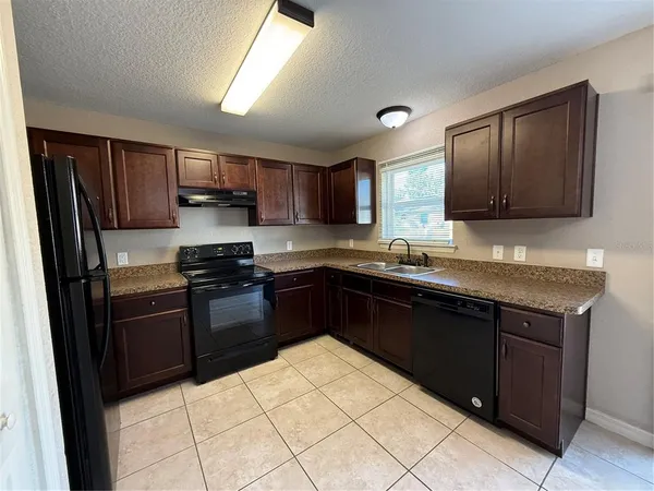 a kitchen with a sink stove top oven and refrigerator