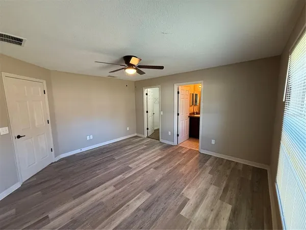 a view of an empty room with window and wooden floor