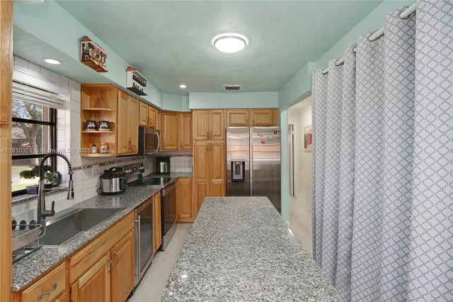 a kitchen with stainless steel appliances granite countertop a refrigerator and a sink