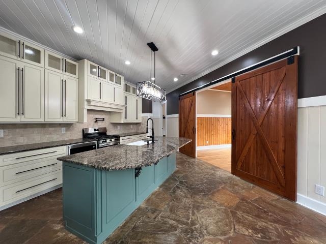 9490 Highway 196 Collierville, TN 38017 - Photo 11 of 40 Kitchen featuring a barn door, a wainscoted wall, glass fronted cabinets, dark stone counters, and two tone cabinets