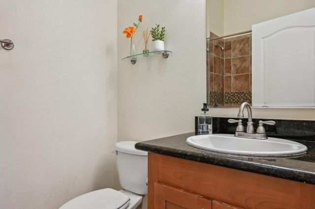 a bathroom with a granite countertop sink toilet and a mirror