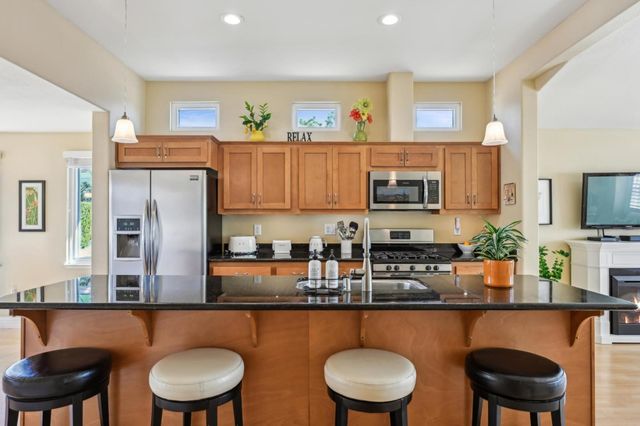 a kitchen with stainless steel appliances granite countertop a table chairs in it and wooden floors
