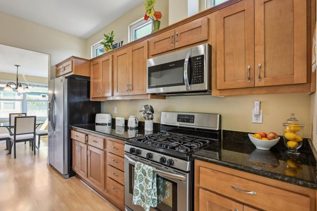 a kitchen with stainless steel appliances granite countertop a stove a sink dishwasher and cabinets with wooden floor