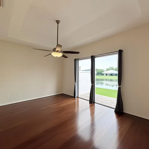 a view of a room with wooden floor a ceiling fan and a window