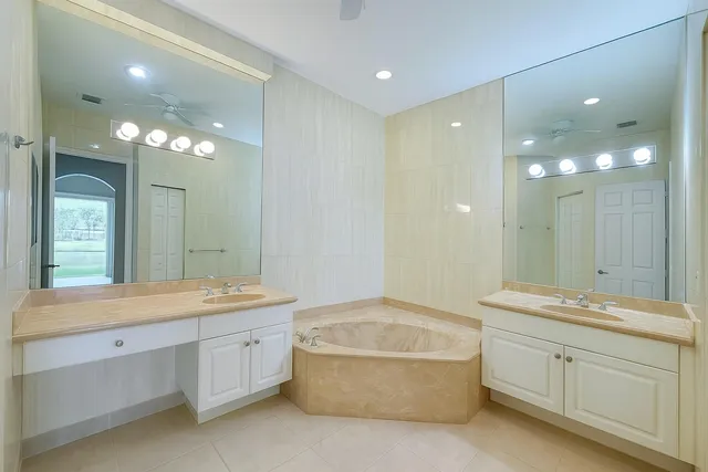 a spacious bathroom with a double vanity sink a large mirror and a bathtub