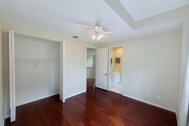 an empty room with wooden floor and ceiling fan
