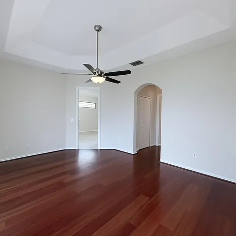 a view of a room with wooden floor a ceiling fan and a window