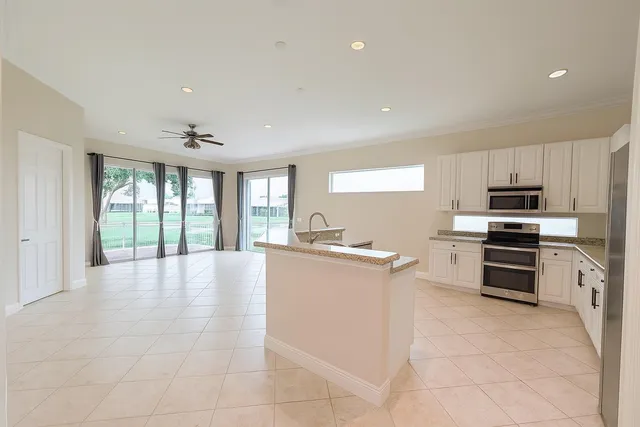 a large kitchen with kitchen island granite countertop a stove top oven a sink a counter space and cabinets