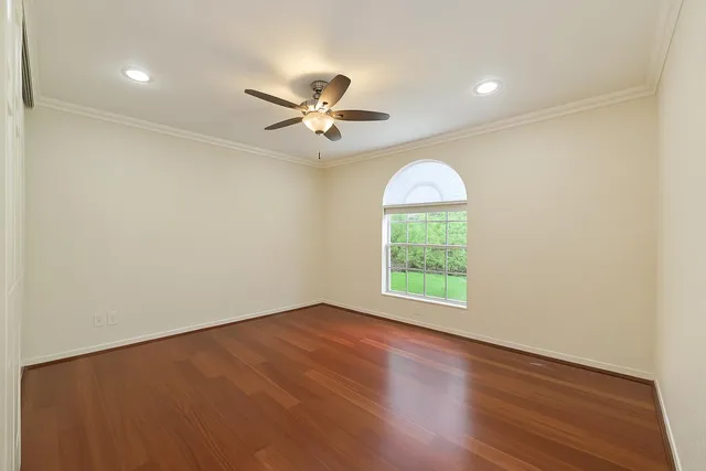 an empty room with wooden floor chandelier fan and windows