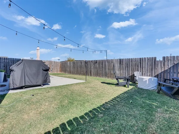 a view of a backyard with table and chairs potted plants and wooden fence