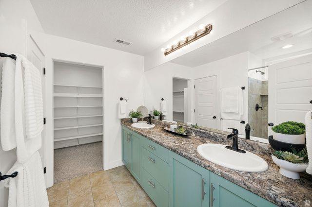 1552 Sumac Drive Logan, UT 84321 - Photo 23 of 72 Bathroom vanity featuring dual sinks with matte black fixtures, extensive countertop space, and light teal cabinetry