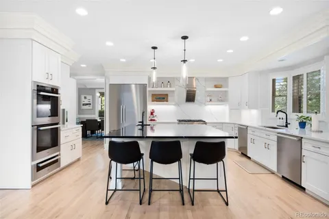 a kitchen with stainless steel appliances kitchen island granite countertop a table chairs sink refrigerator and cabinets