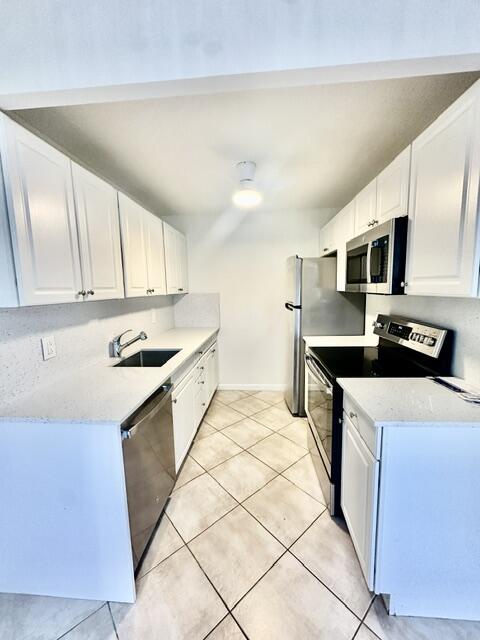 1047 Exeter C Boca Raton, FL 33434 - Photo 3 of 37 a kitchen with granite countertop a sink a stove top oven and cabinetry