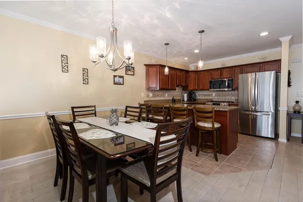 a kitchen with a dining table chairs stainless steel appliances and cabinets