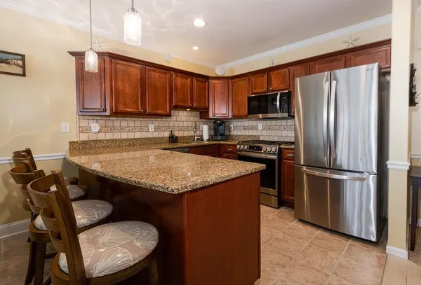 a kitchen with stainless steel appliances granite countertop a refrigerator a stove a sink and a microwave