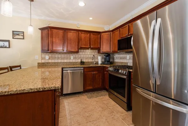 a kitchen with stainless steel appliances granite countertop a refrigerator a stove and a sink with wooden floor