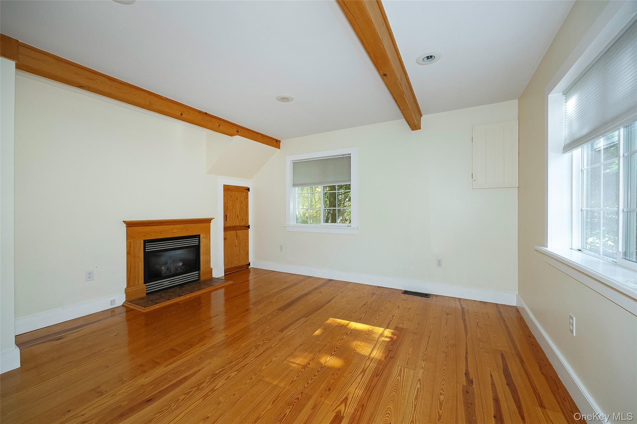 2 Haggerty Hill Road Rhinebeck, NY 12572 - Photo 7 of 47 Unfurnished living room with a glass covered fireplace, wood finished floors, and beam ceiling