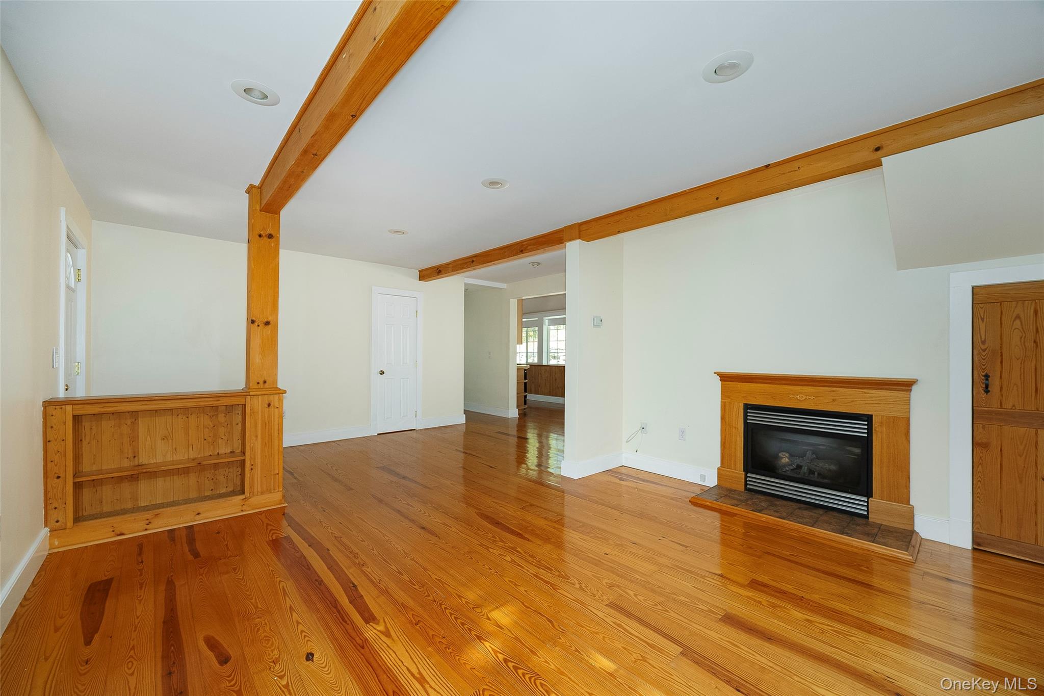 2 Haggerty Hill Road Rhinebeck, NY 12572 - Photo 9 of 47 Unfurnished living room featuring beamed ceiling, a glass covered fireplace, and light wood finished floors