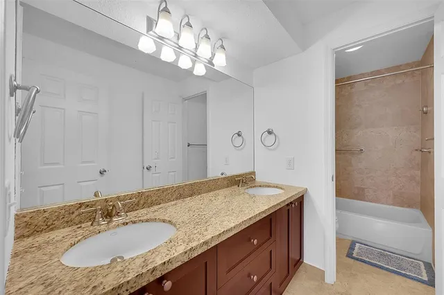 a bathroom with a granite countertop sink a mirror and a shower