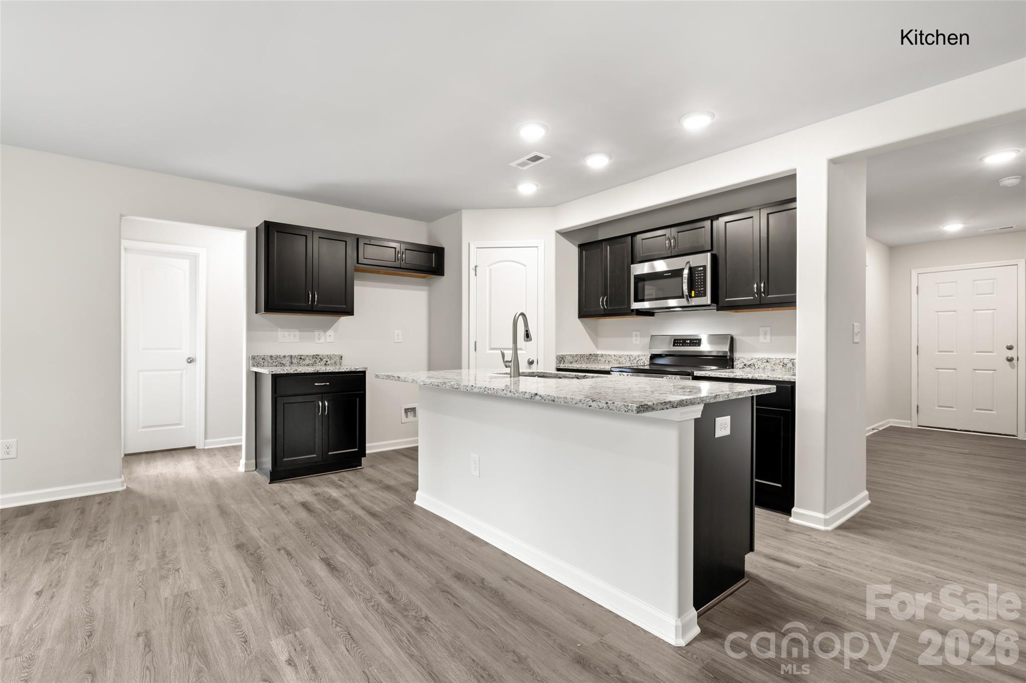 302 Elm Street Lancaster, SC 29720 - Photo 3 of 25 a kitchen with kitchen island granite countertop a stove top oven a sink dishwasher a refrigerator and a microwave oven with wooden floor