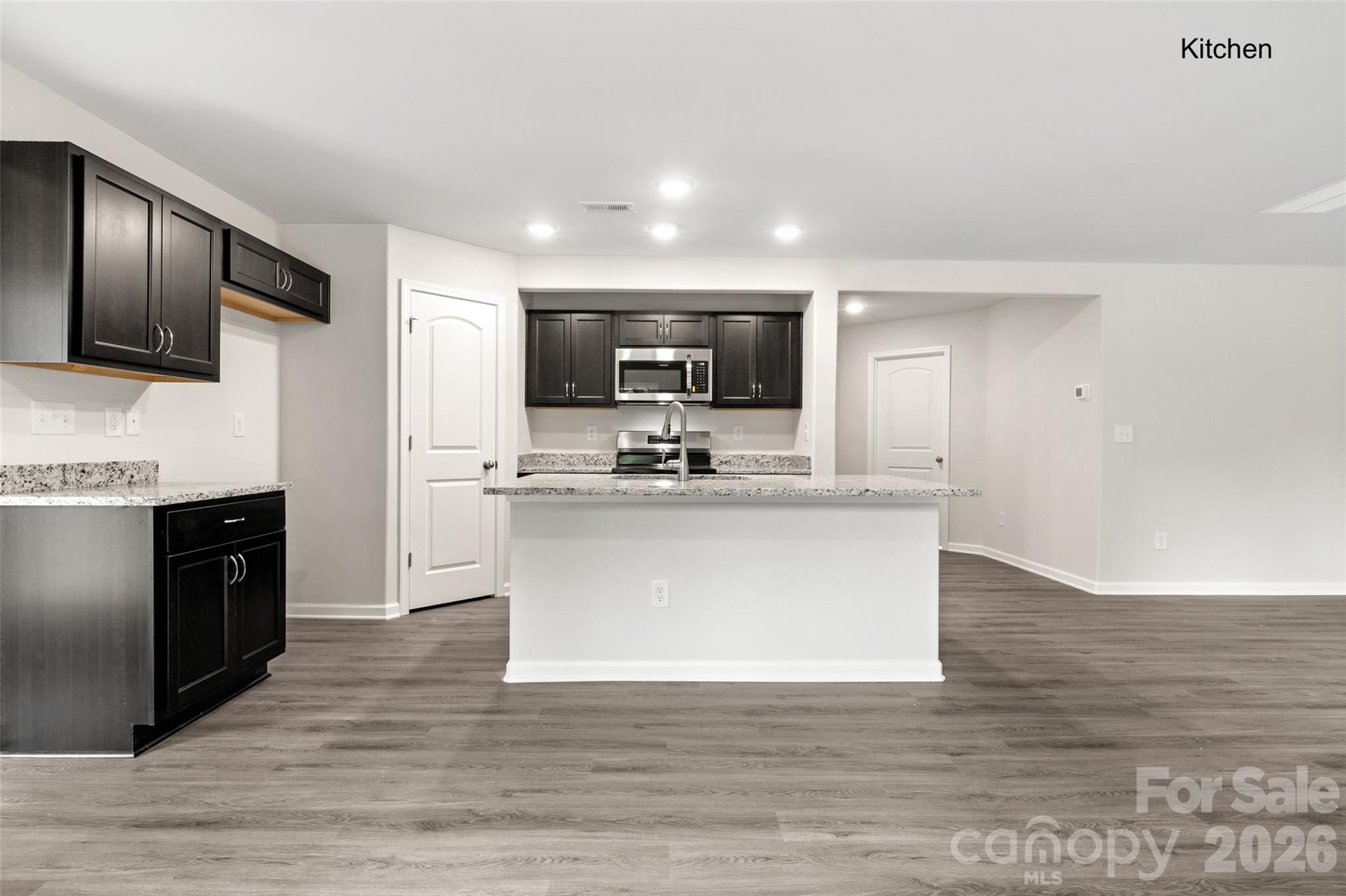 302 Elm Street Lancaster, SC 29720 - Photo 4 of 25 a view living room with stainless steel appliances kitchen island granite countertop a stove a sink dishwasher a microwave oven and a refrigerator with wooden floor