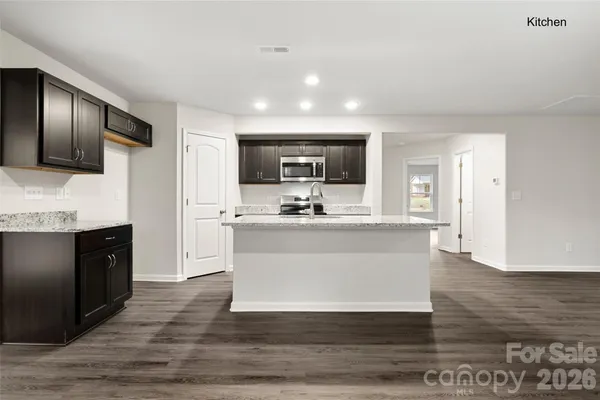 a view of kitchen with stainless steel appliances wooden floor and living room