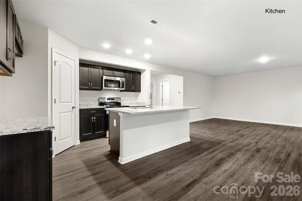 a kitchen with granite countertop a refrigerator stove top oven and sink