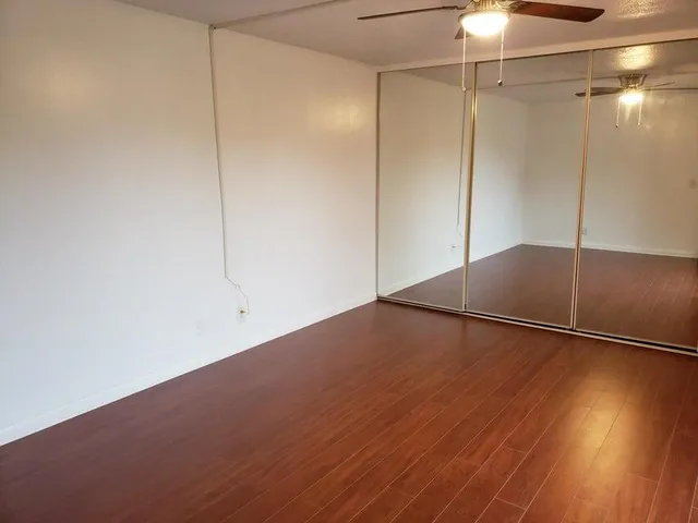 an empty room with wooden floor fan and windows