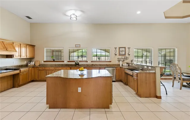 a large kitchen with kitchen island a stove a sink a counter top space and living room view
