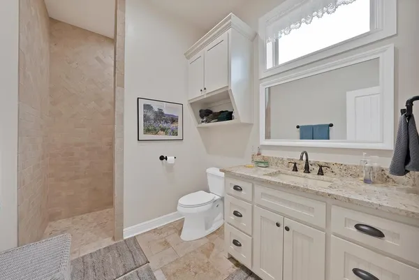 a bathroom with a granite countertop toilet sink and mirror