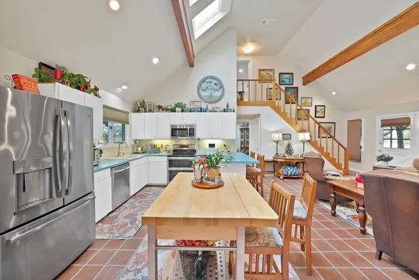 a kitchen with stainless steel appliances granite countertop a stove a refrigerator a dining table and chairs with wooden floor