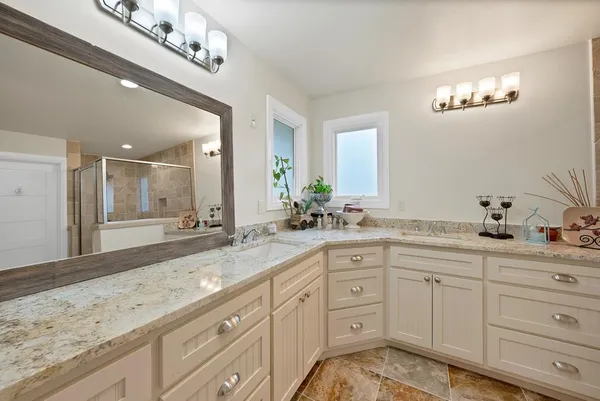 a spacious bathroom with a granite countertop double vanity sink and mirror