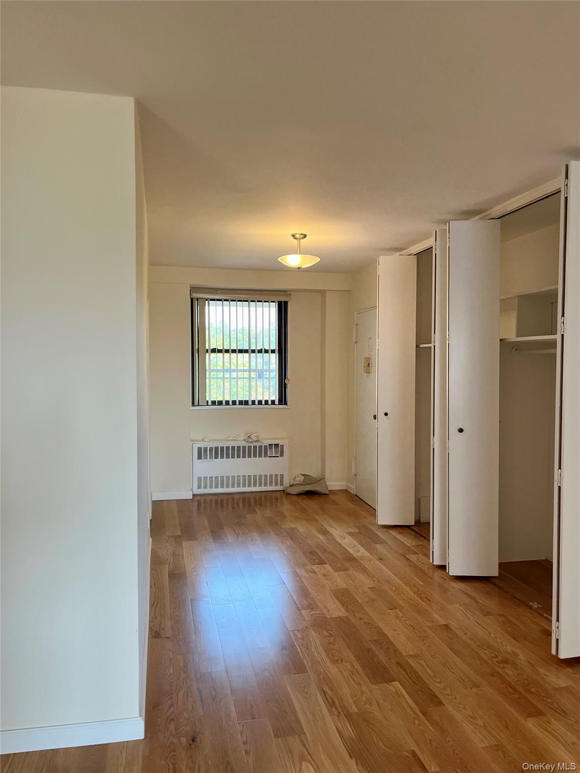 4901 Henry Hudson Parkway West, Unit 9F Bronx, NY 10471 - Photo 5 of 17 an empty room with wooden floor and windows