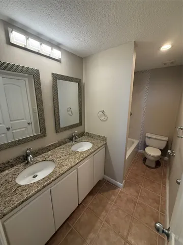 a bathroom with a granite countertop sink toilet and mirror