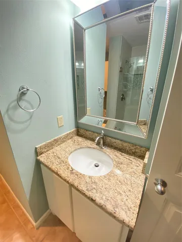 a bathroom with a granite countertop sink and a mirror